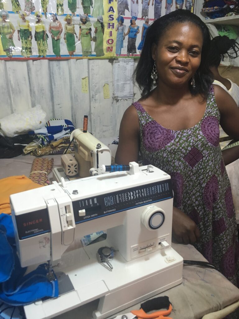 A woman standing next to a sewing machine.