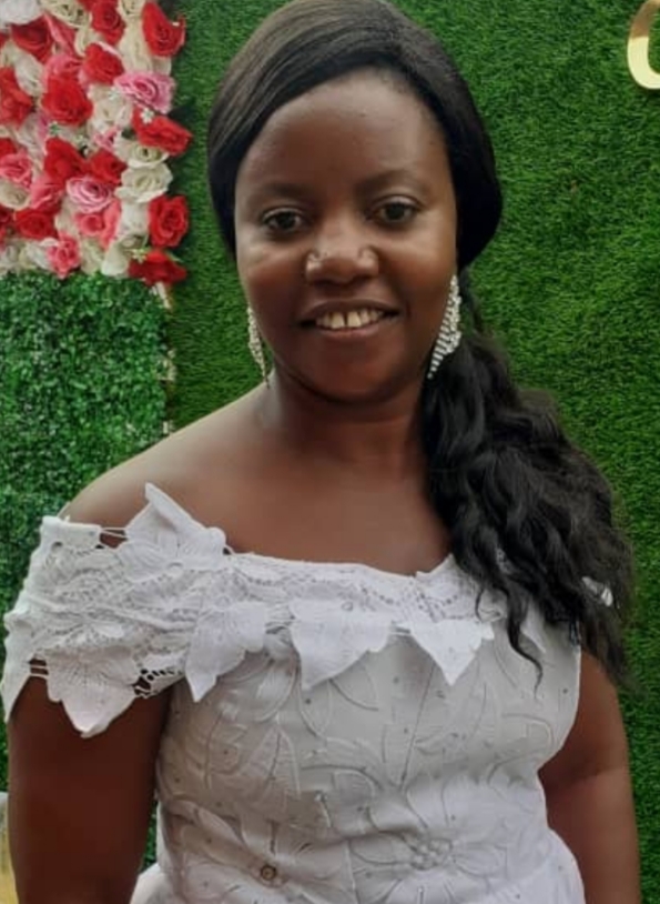 A woman in white dress standing next to green wall.