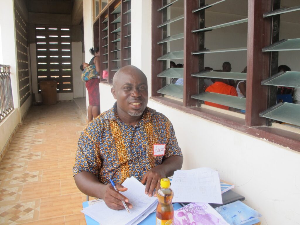 A man sitting at a table with papers and a bottle of beer.