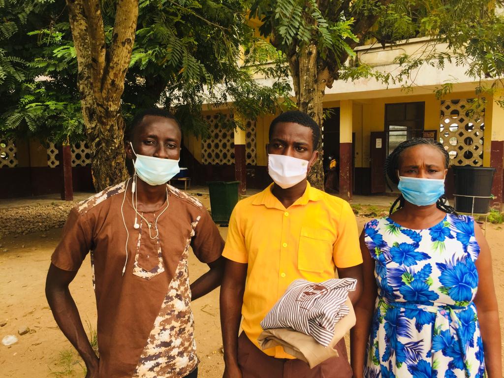 Three people wearing masks standing in front of a building.